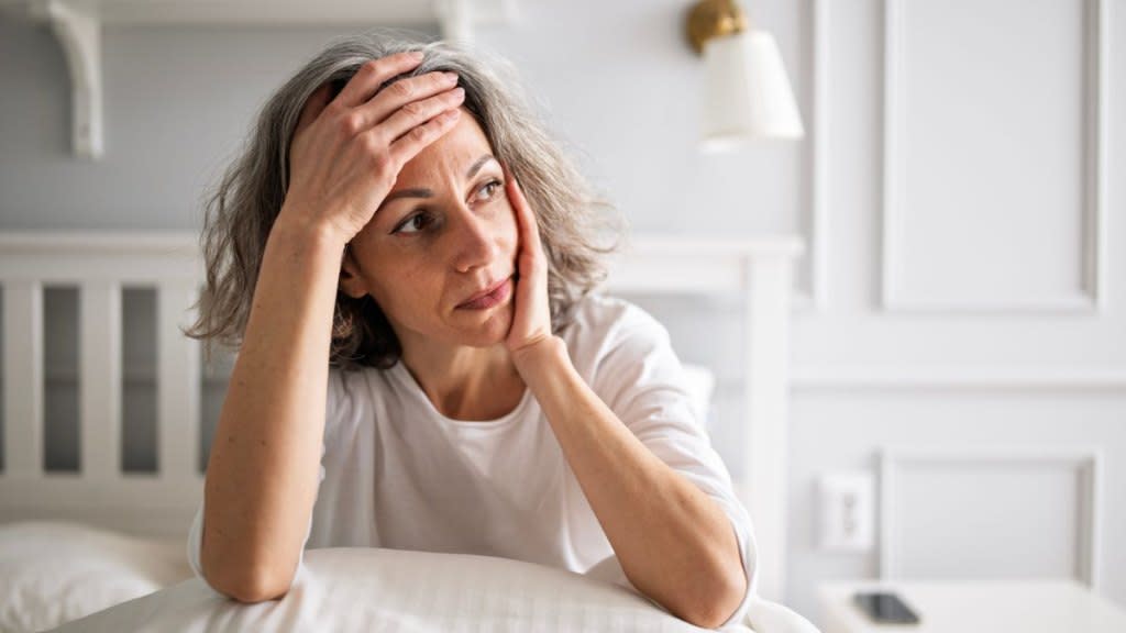 Woman with her hand on her head due to fatigue, a common symptom of liver disease