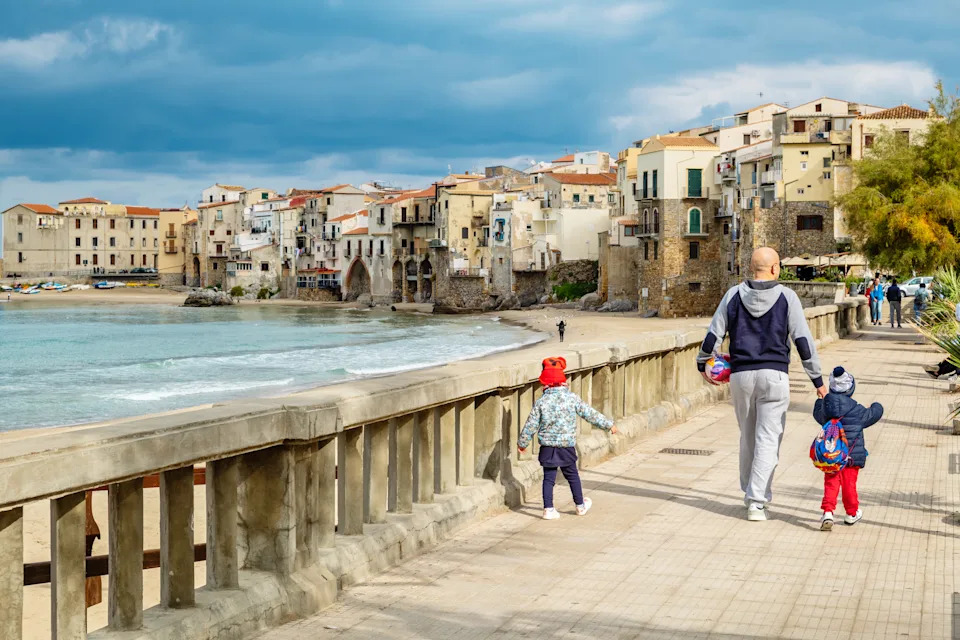 Cefalu, Sicily, Italy - November 17, 2018: People walking alonge sea on a beach promenade