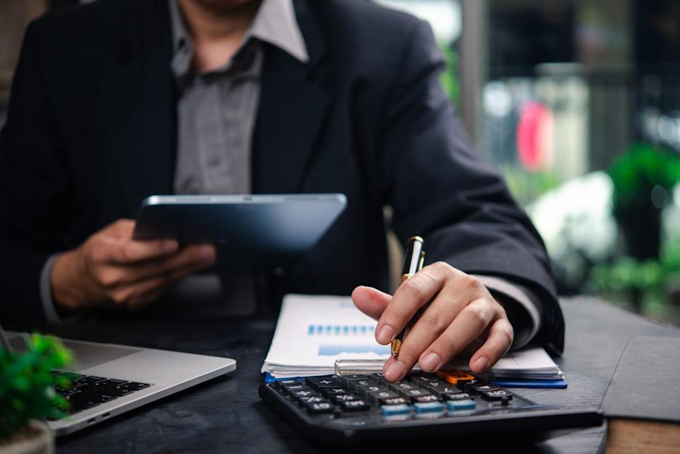 Businessman accountant reviewing financial documents and using a tablet and calculator to plan business strategies and data analysis.