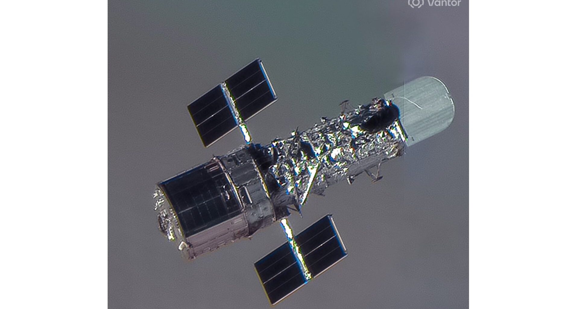 closeup satellite photo of the hubble space telescope, showing it as a shiny silver cylinder with two small solar wings