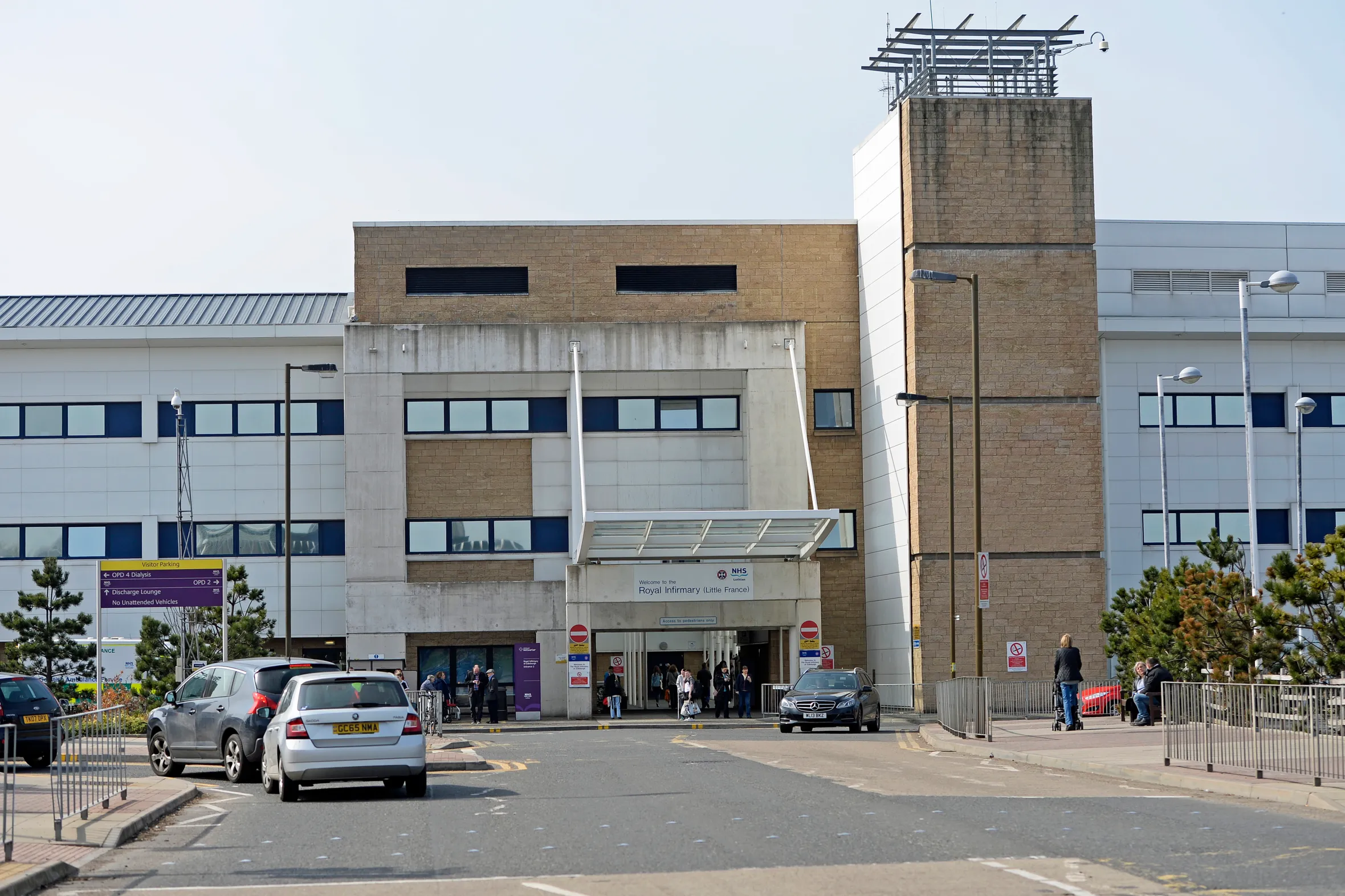 The Royal Infirmary of Edinburgh, with cars driving on a road in front of the hospital building.