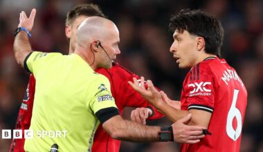Referee Paul Tierney speaks with Lisandro Martinez of Manchester United after showing him a red card for pulling the hair of Dominic Calvert-Lewin of Leeds United
