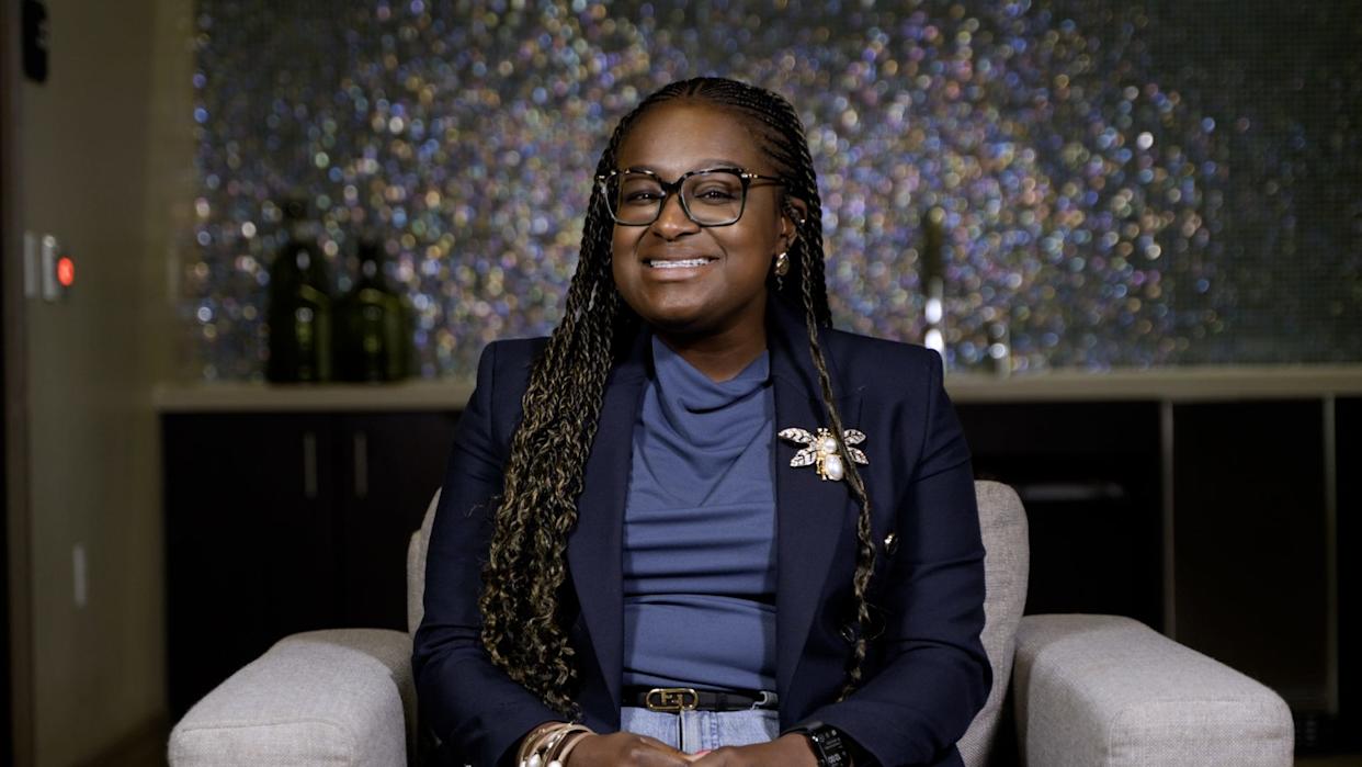 Camille Stewart Gloster sitting in a white chair in a blue shirt.
