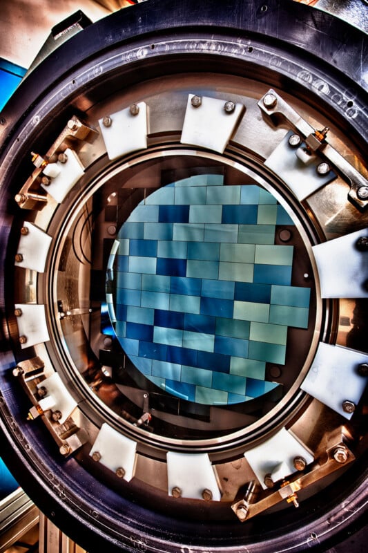 A close-up view of a large scientific camera sensor, featuring multiple rectangular blue-green segments arranged in a circular pattern within a round metal and plastic frame.