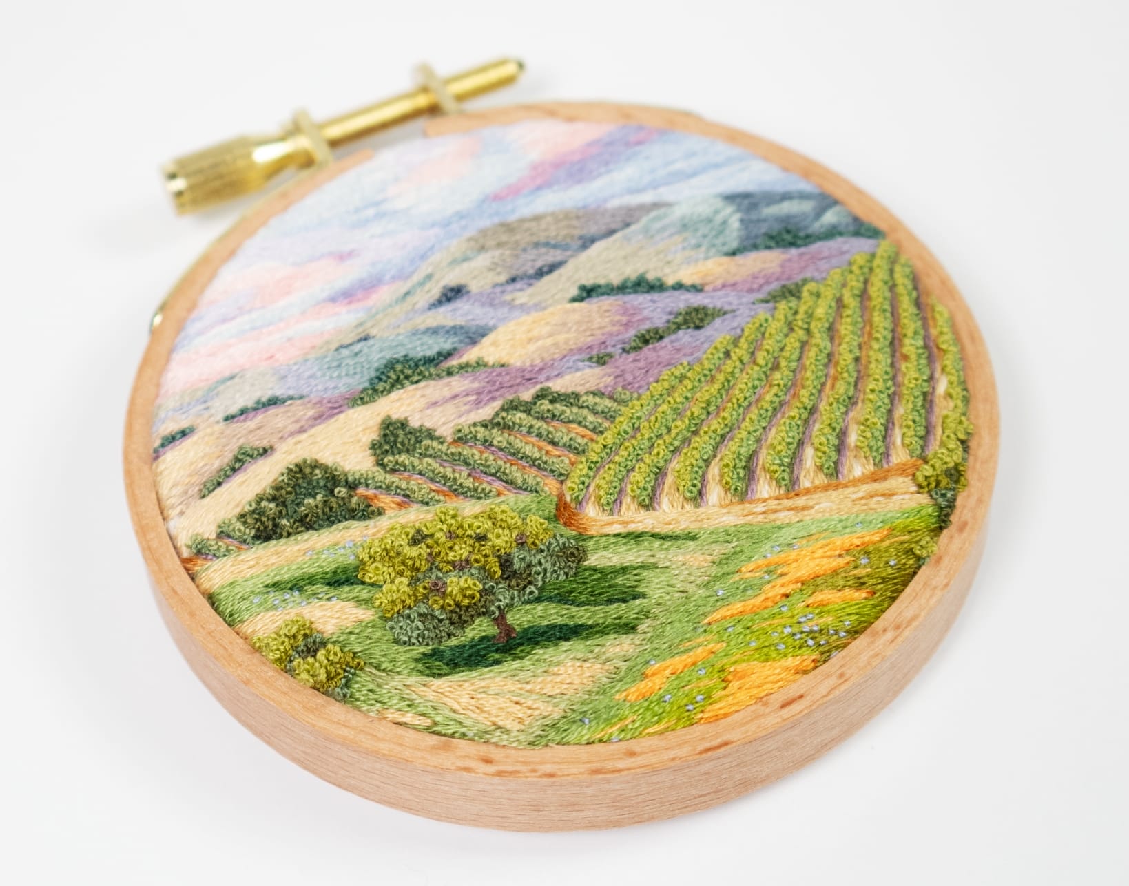a lush landscape embroidery in a light wood hoop by Cassandra Dias