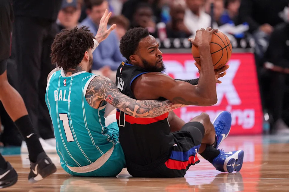 Hornets guard LaMelo Ball (1) and Pistons forward Paul Reed (7) scramble for the loose ball during the second half at Spectrum Center.