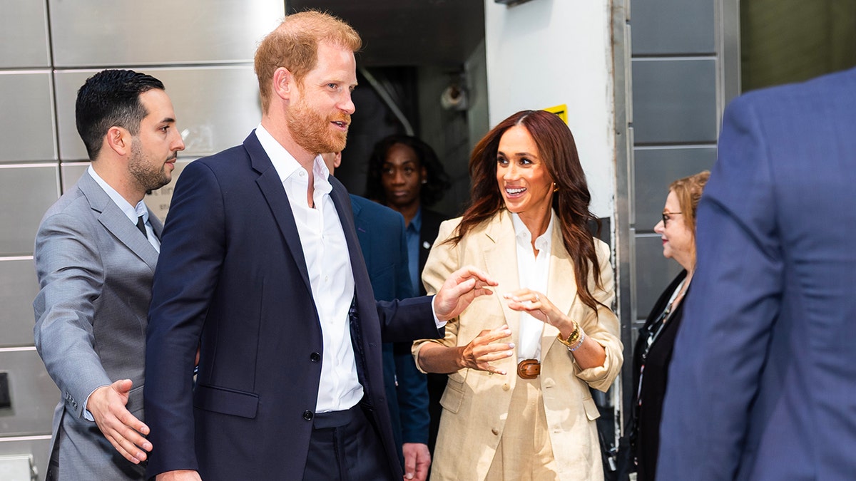 Prince Harry and Meghan Markle walking outside at Time100 Summit in New York City surrounded by bodyguards