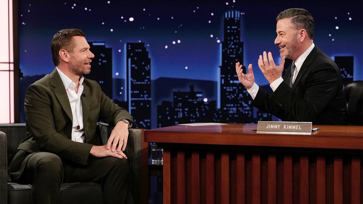 Eric Swalwell and Jimmy Kimmel standing together on a television set.