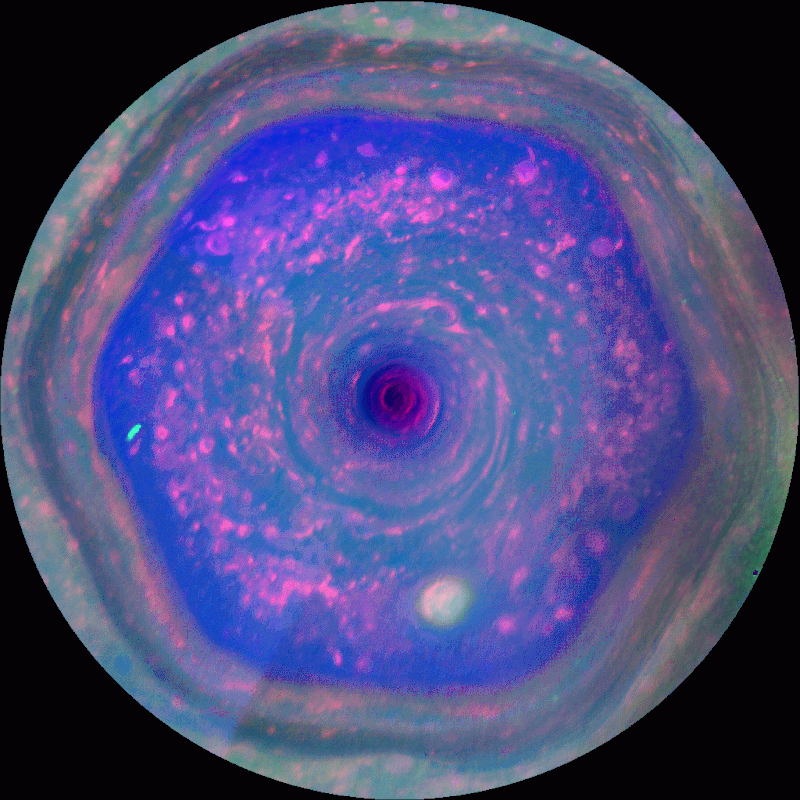 False-color image of Saturn’s north polar vortex, featuring a hexagonal storm pattern with swirling clouds in shades of blue, purple, and pink.