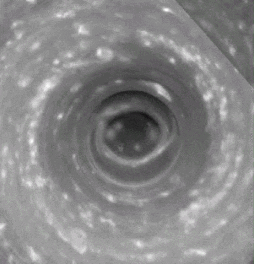 Black and white image of a swirling vortex pattern, possibly resembling a whirlpool or spiral formation with scattered light spots throughout.