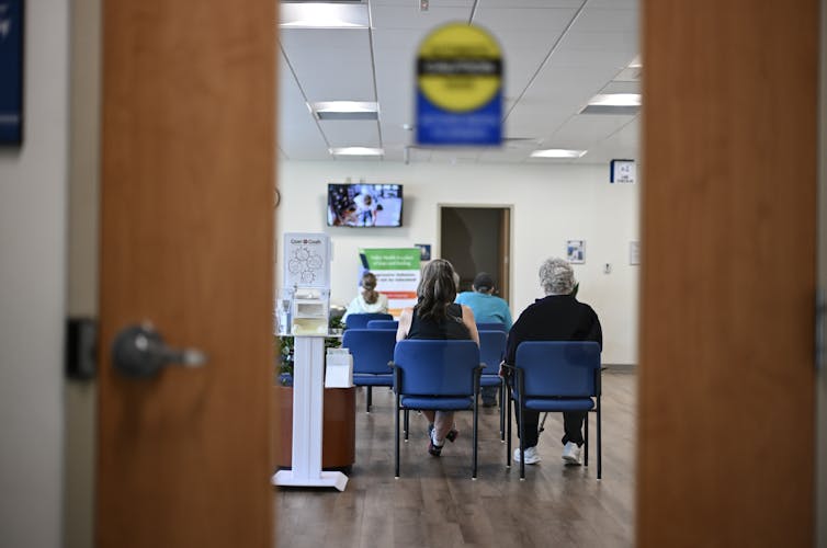 View of people sitting in blue chairs in hospital waiting room
