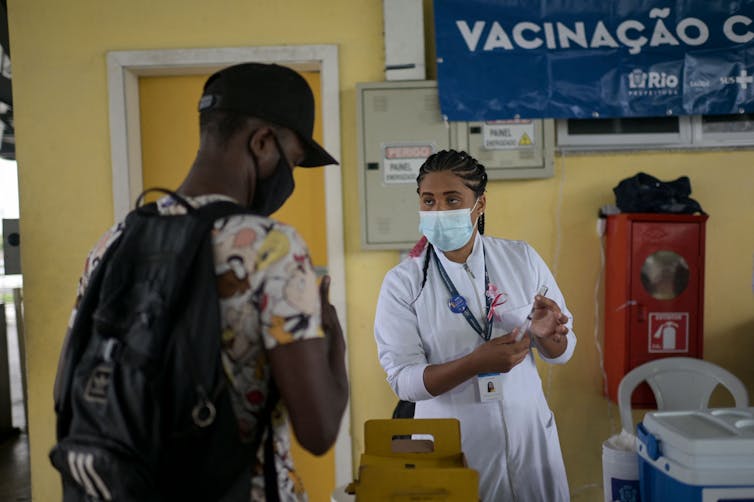 A commuter wearing a facemask gets his COVID-19 vaccine at a Rio de Janeiro bus station.