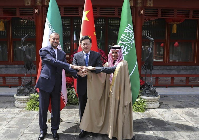 Three men greet during a diplomatic meeting.