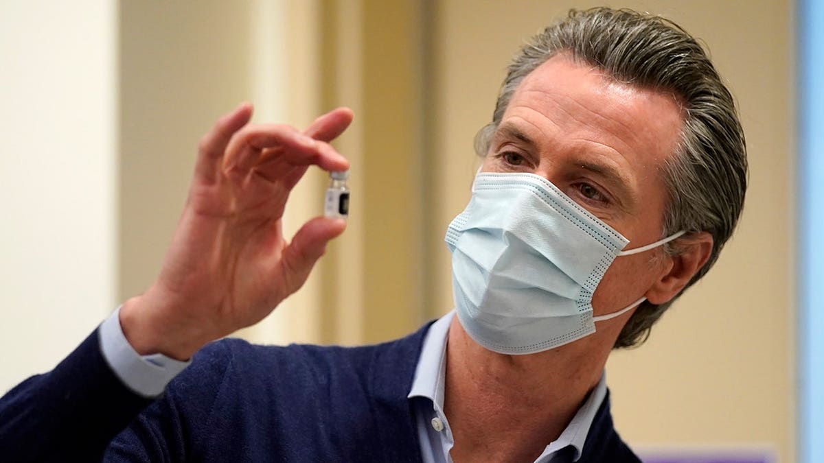 Gov. Gavin Newsom holding a vial of Pfizer-BioNTech COVID-19 vaccine at Kaiser Permanente Los Angeles Medical Center