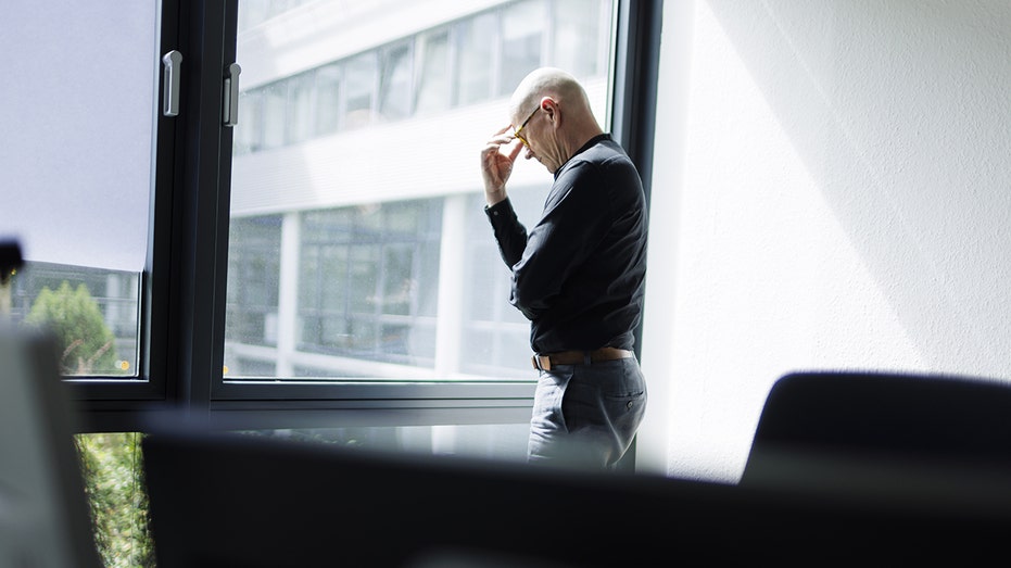 Man looks stressed by office window