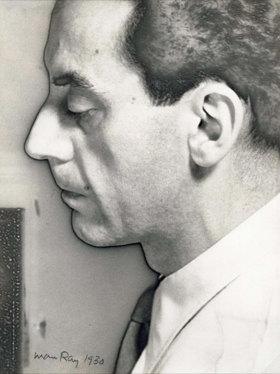 A close-up black-and-white portrait of a man in profile by Man Ray, with dramatic shadows emphasizing his facial features.