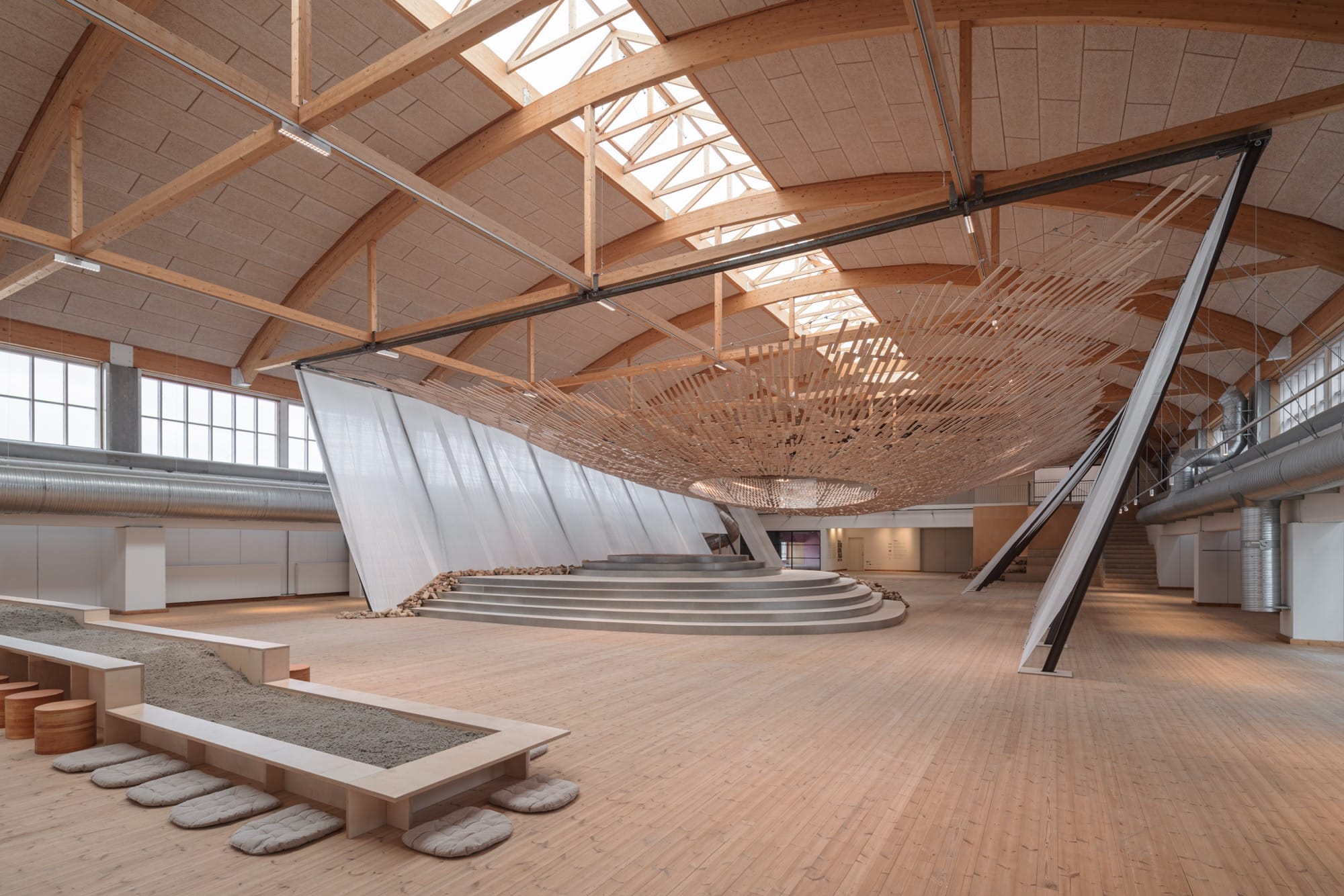 light streams through a wooden canopy in a large scale installation of wood and brick by Kengo Kuma