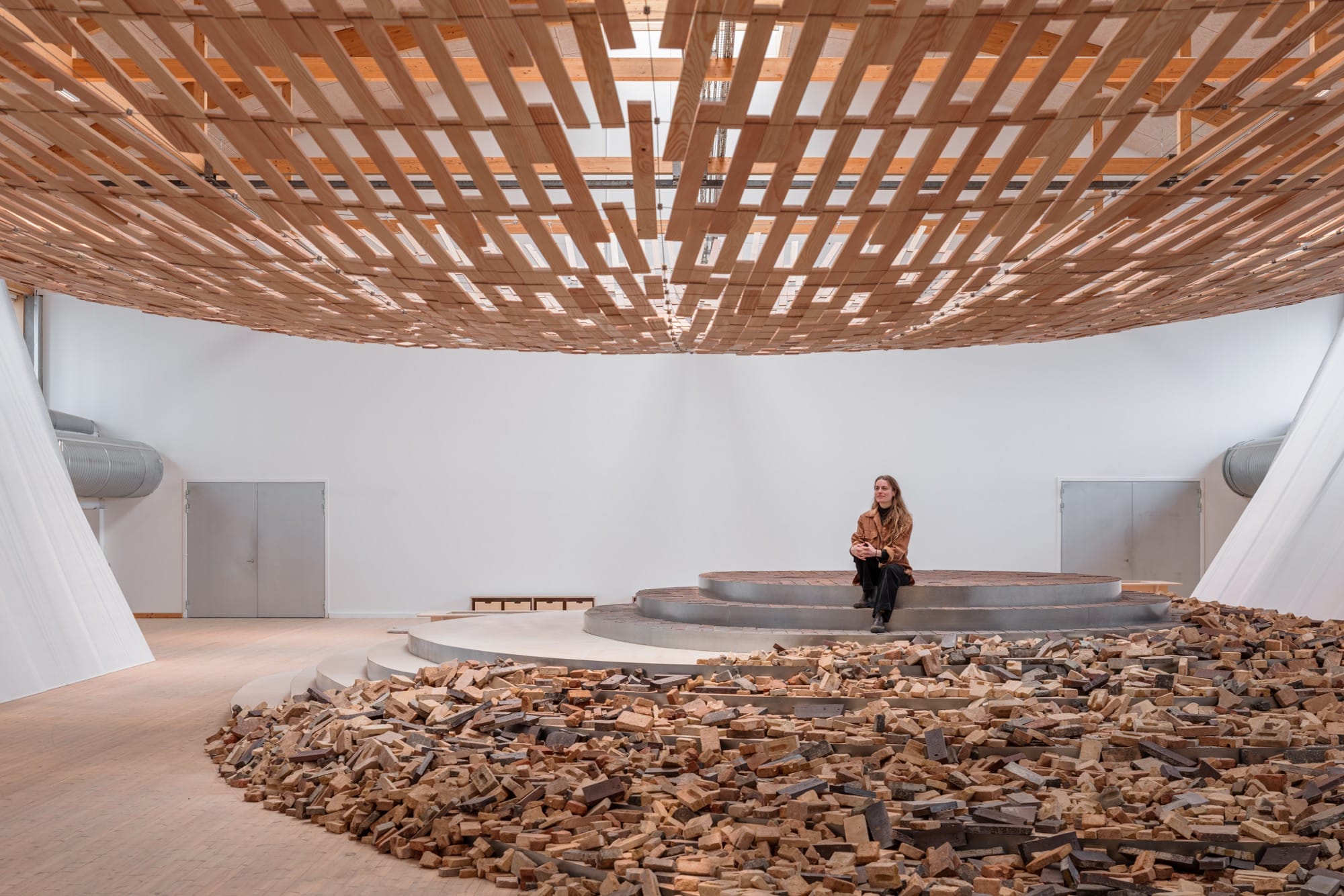 visitors enjoy an installation in which light streams through a wooden canopy by Kengo Kuma