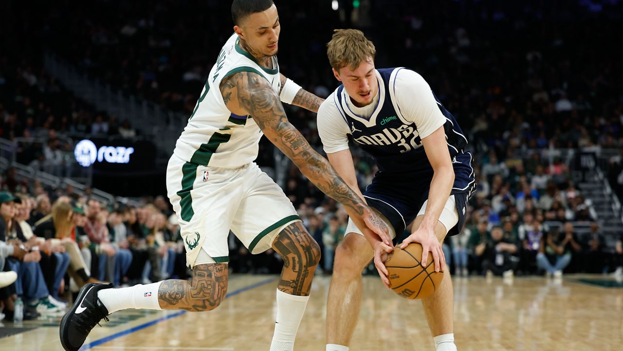 Milwaukee Bucks forward Kyle Kuzma (18) and Dallas Mavericks forward Cooper Flagg (32) reach for the ball during the first half of an NBA basketball game Tuesday, March 31, 2026, in Milwaukee.