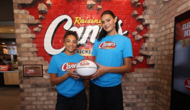 UCLA stars Lauren Betts and Kiki Rice posing with a basketball inside a Raising Cane’s restaurant in Hollywood after winning the 2026 NCAA Championship.