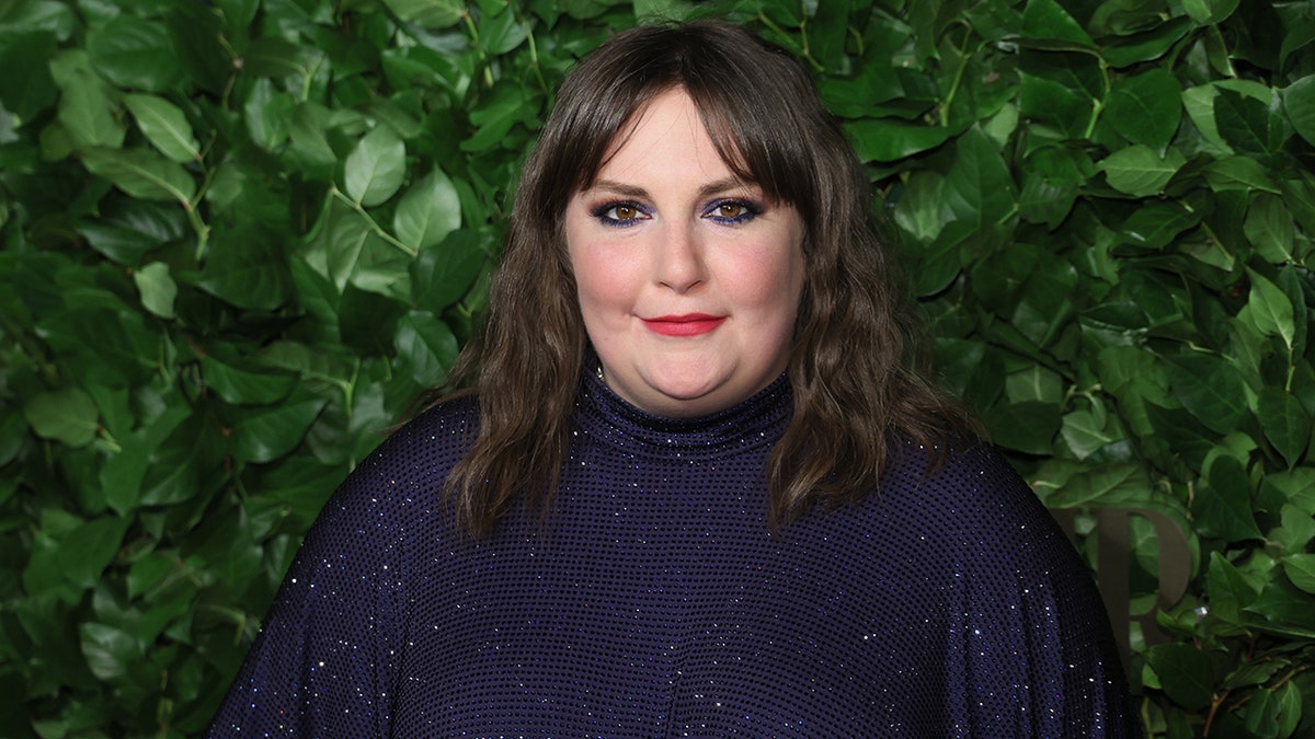 Lena Dunham standing on carpet wearing a blue sparkly dress in New York City