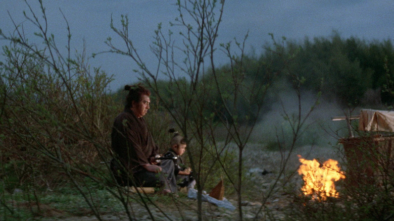 Tomisaburo Wakayama as Itto and Akihiro Tomikawa as Daigoro, sitting by the fire in Lone Wolf and Cub: Baby Cart at the River Styx