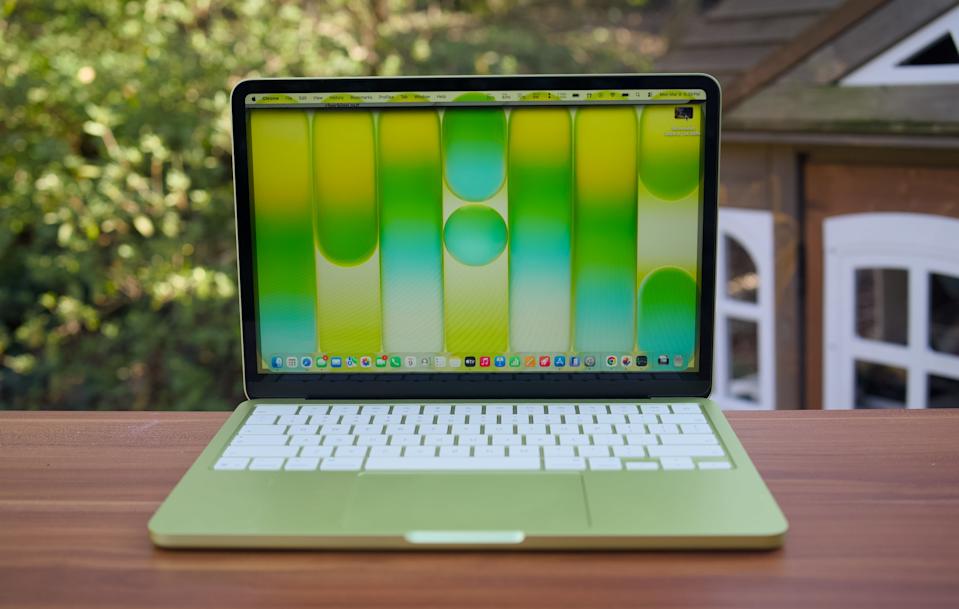 A citrus MacBook Neo on a table outside.