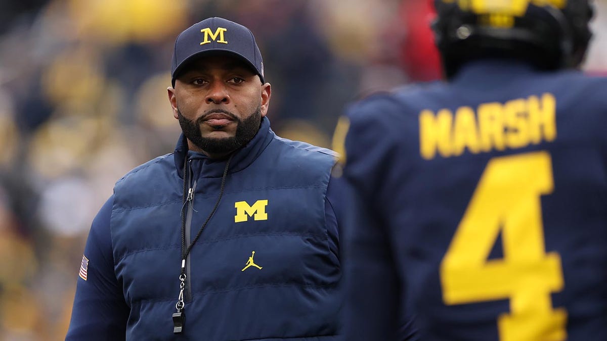 Sherrone Moore standing on the field during warmups at Michigan Stadium