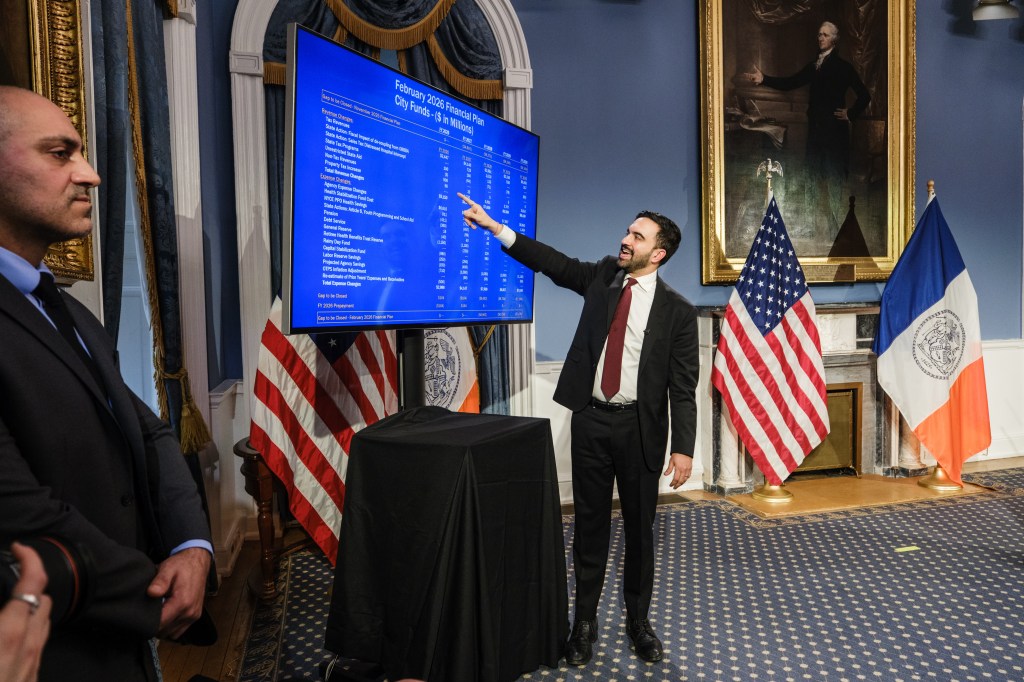 Director of the New York City Mayor's Office of Management and Budget (OMB) Sherif Soliman points to the "February 2026 Financial Plan" on a large screen during a press conference.