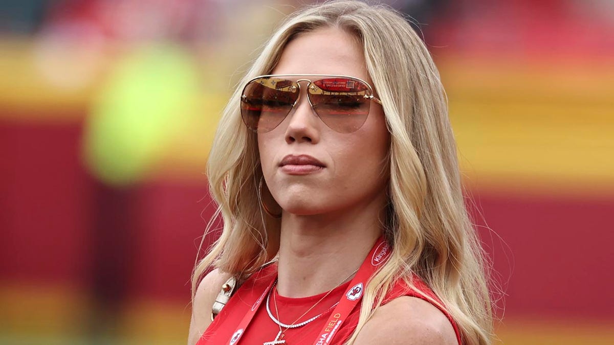 Gracie Hunt standing on the sidelines at GEHA Field at Arrowhead Stadium during an NFL game.