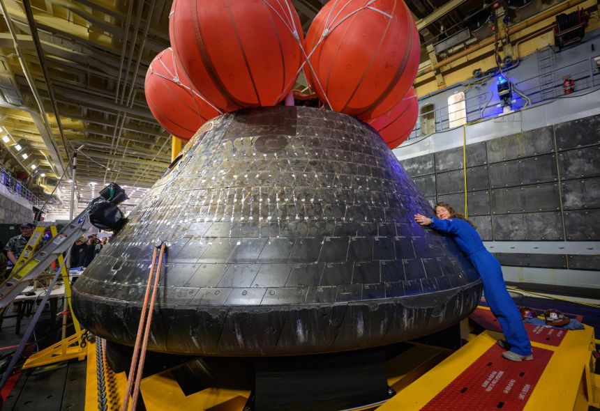 Artemis II astronaut Christina Koch hugs the Orion spacecraft in the well deck of USS John P. Murtha on April 11, one day after the crew splashed down off the coast of California.