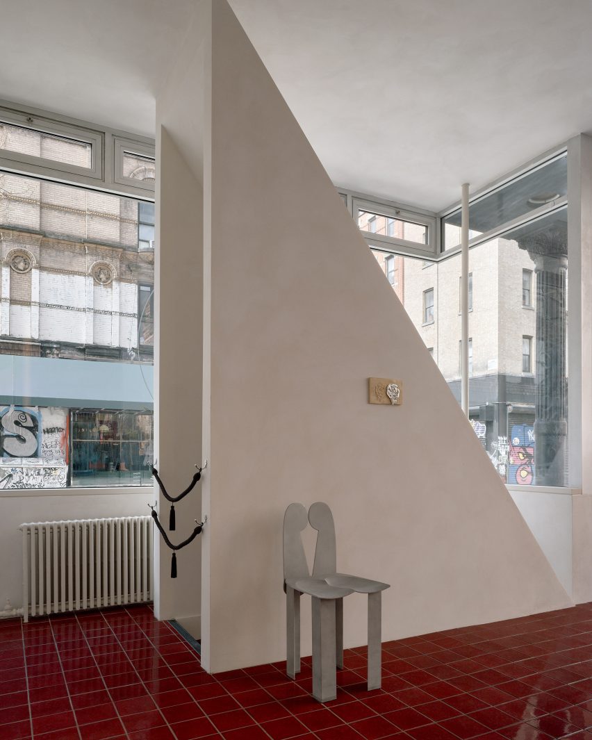 Triangular walls disguise a staircase bulkhead and provide a backdrop for an aluminium chair by Minjae Kim