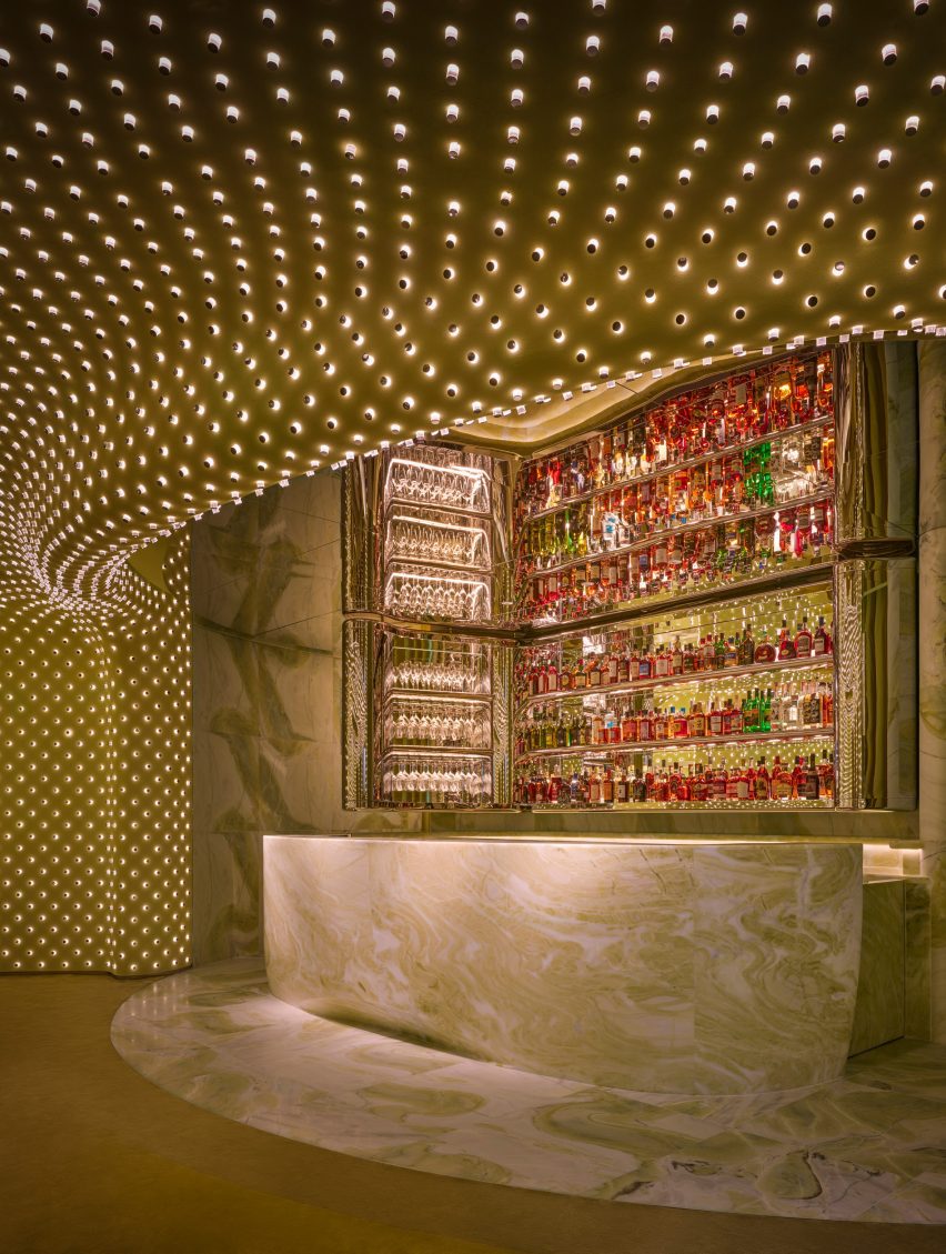 Green marble forms a service counter and a mirrored ceiling reflects a liquor bottle display behind