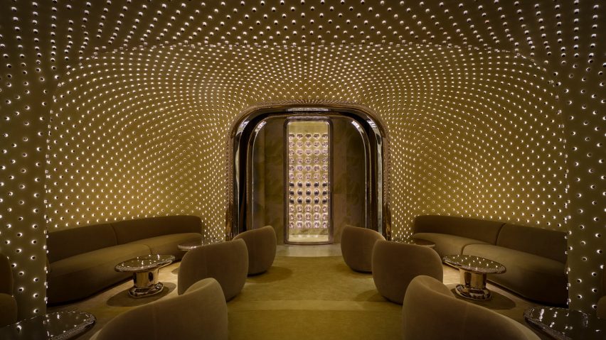 Curvaceous sofas are tucked into alcoves, and lights reflect off stainless steel tables and an arched door frame