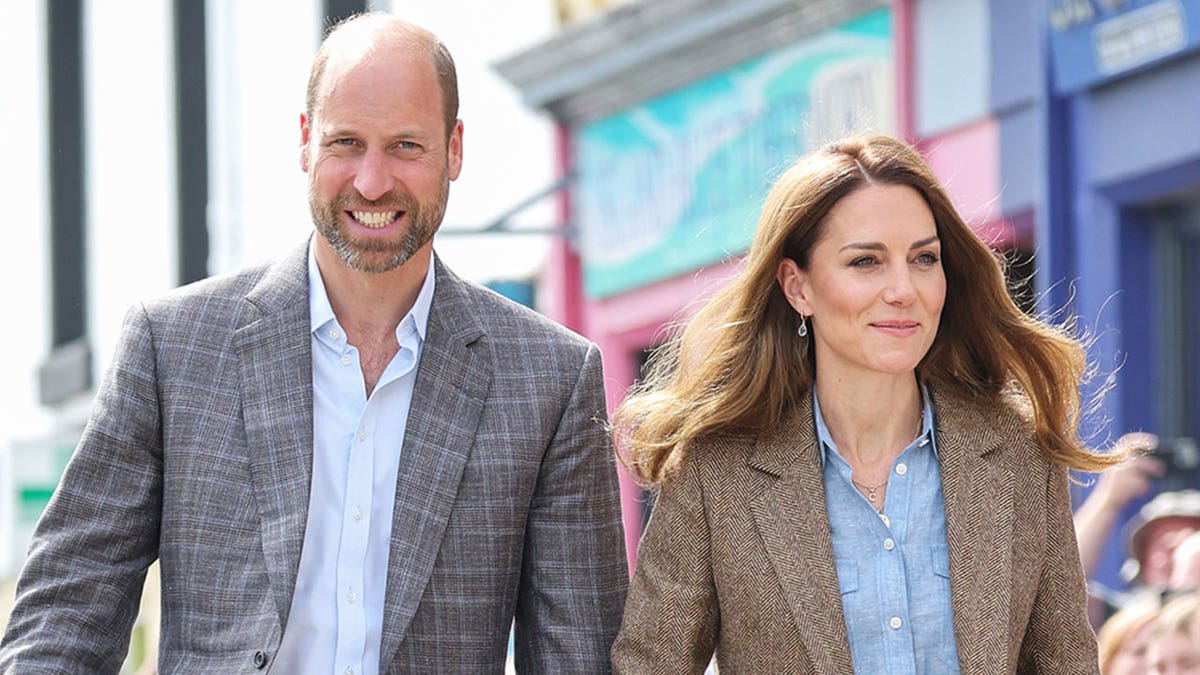 Prince William and Catherine, Princess of Wales, smiling and walking side-by-side in Tobermory, Scotland