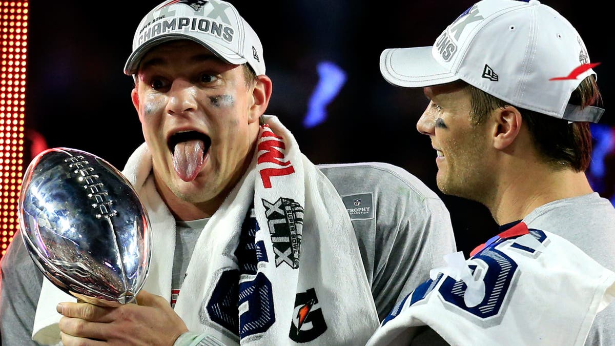Rob Gronkowski and Tom Brady holding Vince Lombardi Trophy celebrating on field