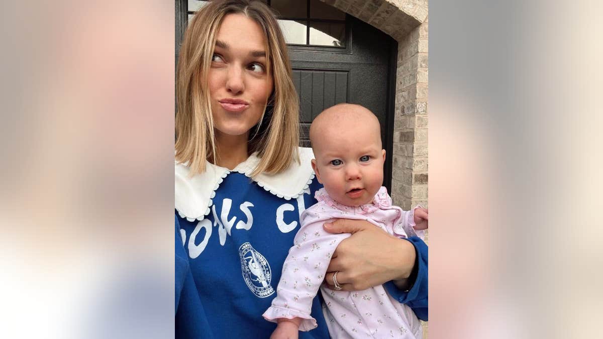 Sadie Robertson holding her daughter kit and looking to the side