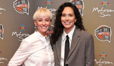 Two people smiling at the Basketball Hall of Fame event, with logos and a Mohegan Sun backdrop.