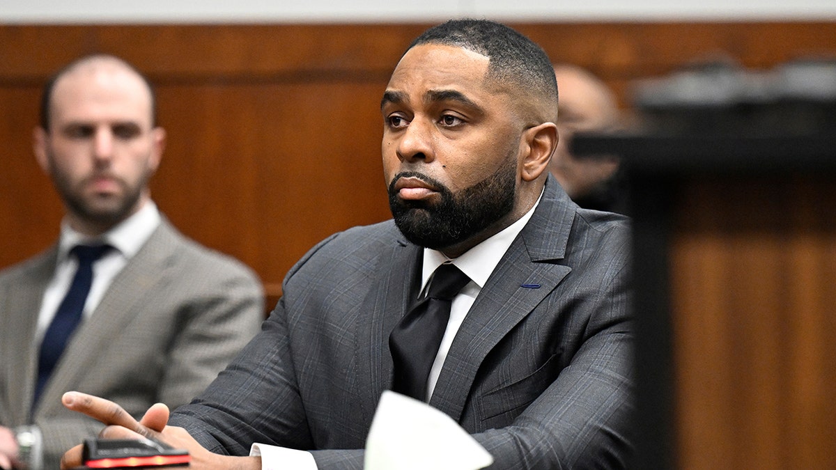 Former Michigan football coach Sherrone Moore standing in a courtroom in Ann Arbor
