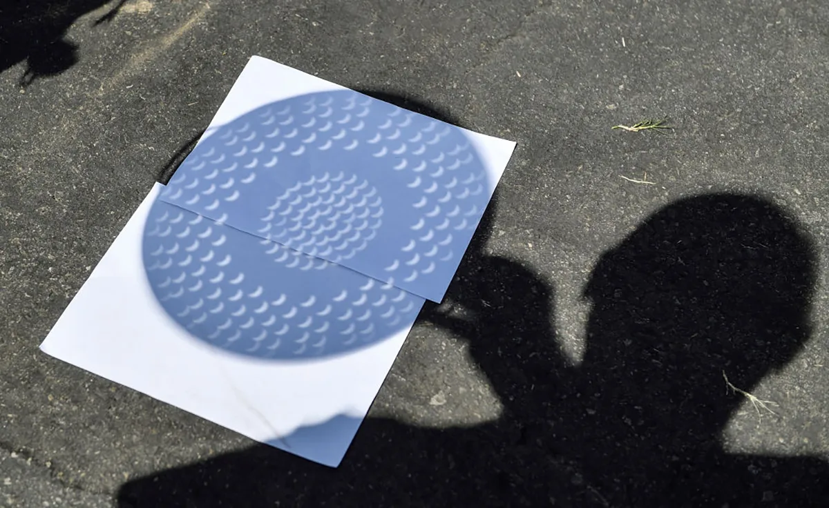 A kitchen colander can be used to project the shadow of lots of mini solar eclipses on the ground! Photo by Jeff Gritchen/Orange County Register via Getty Images