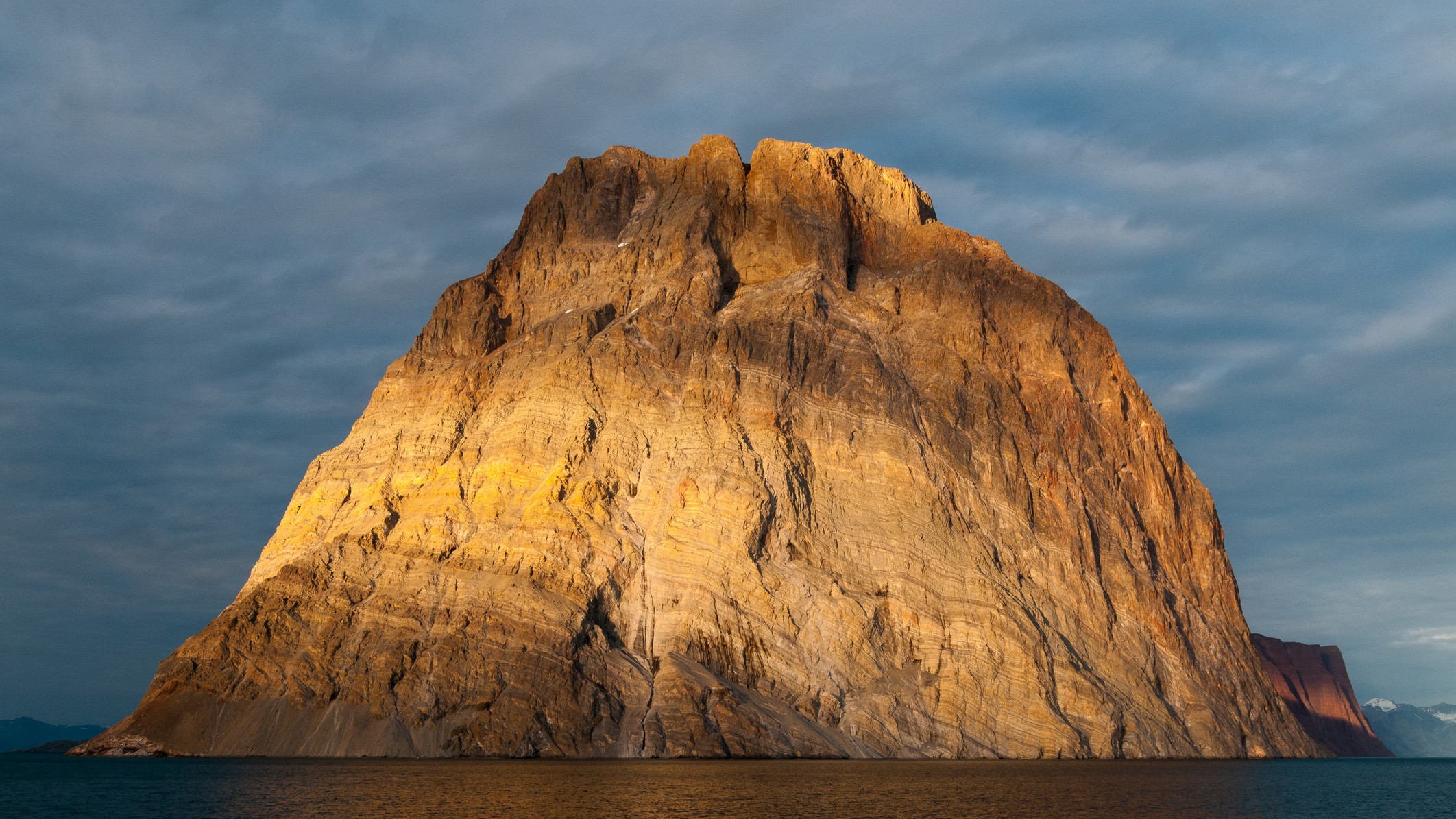 a large rocky island bathed in golden light from the setting sun.