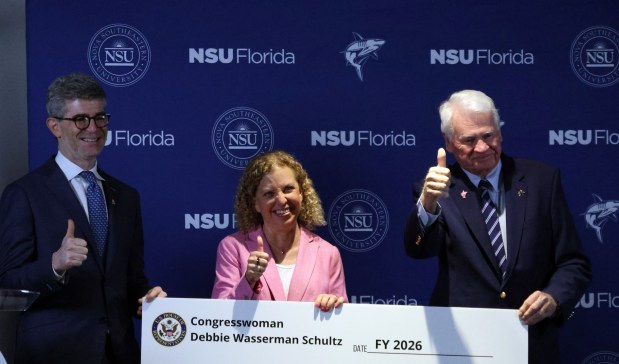 Nova Southeastern University Chief Medical Officer Dr. Chad Perlyn, left, and NSU President Dr. Harry Moon, right, join U.S. Rep. Debbie Wasserman Schultz (D-Fla.) on the Davie campus on Wednesday, April 8, 2026. Wasserman Schultz announced more than $1 million in federal investment she secured to improve the treatment of brain cancer. (Joe Cavaretta/South Florida Sun Sentinel)