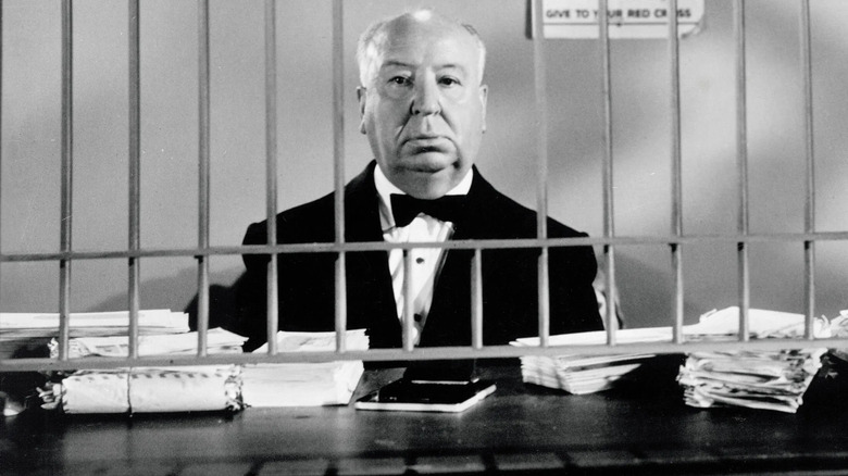 Alfred Hitchcock stands behind bars in The Alfred Hitchcock Hour.