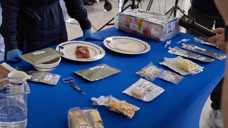 A food scientist showing reporters what the Artemis II menu items look like spread out on a table.