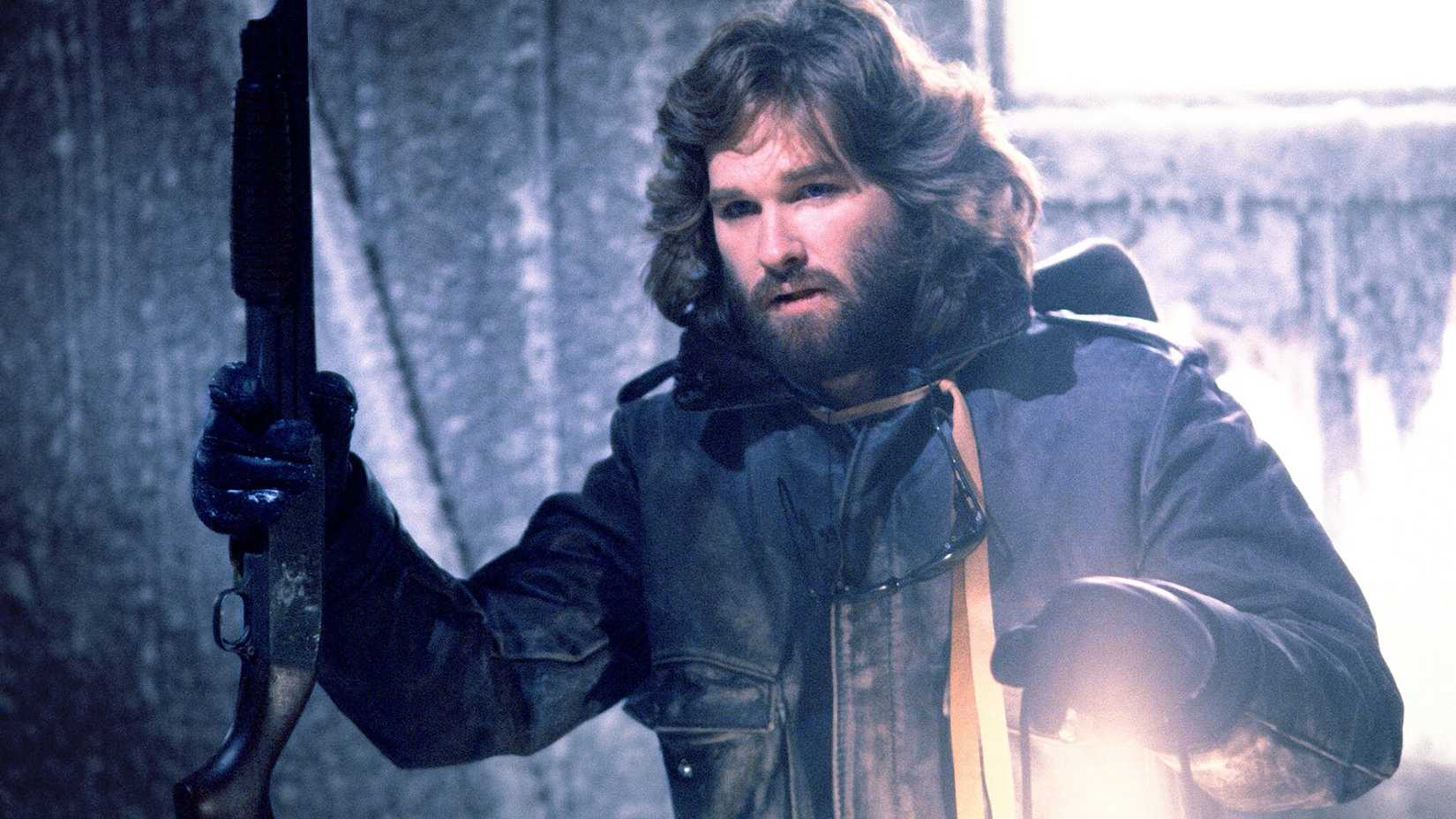 Kurt Russell holds a gun and a lantern in the Thing