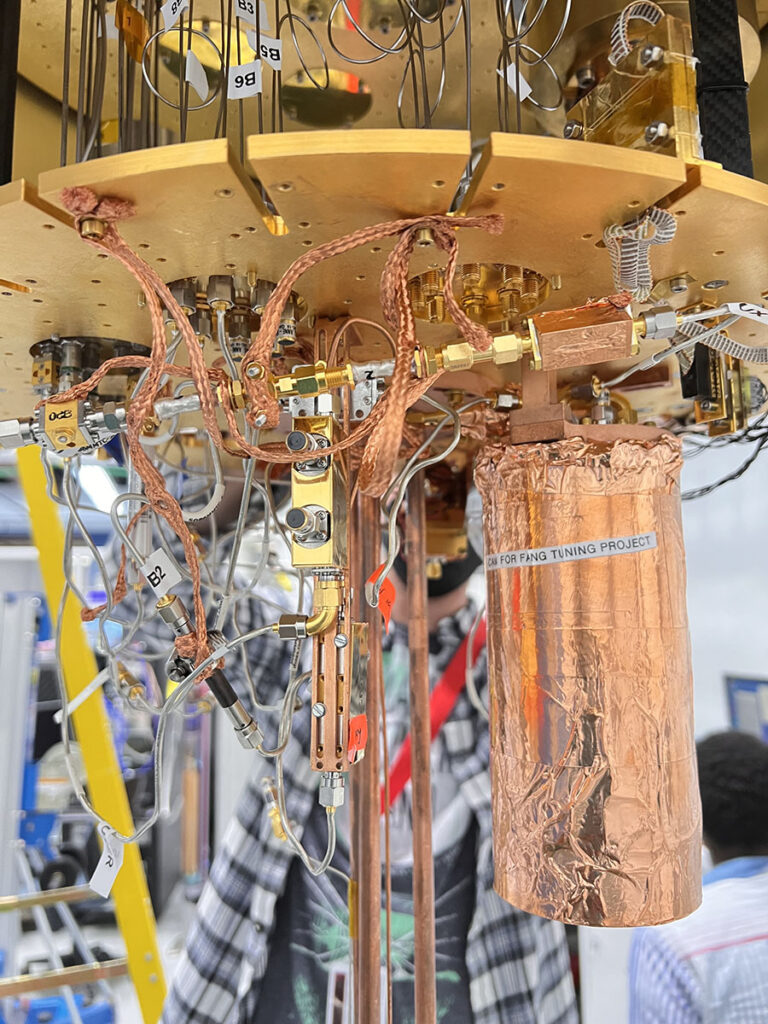 Setup of an experiment at Fermilab to test use of an ultrasensitive detector to search for evidence of dark photons, a hypothetical particle of dark matter. Housed within a dilution refrigerator kept at cryogenic temperatures, the copper wrapped mu-metal can, at right, contains the detector. Credit: Fang Zhao, Fermilab