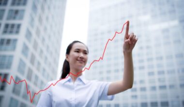 An investor traces a line upward in the air while standing outside in a city.