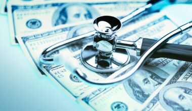 A stethoscope sits atop $100 bills spread across a white table.