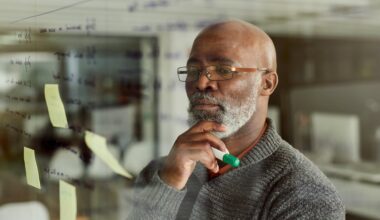 A person with hand on chin, holding a marker, thinking.
