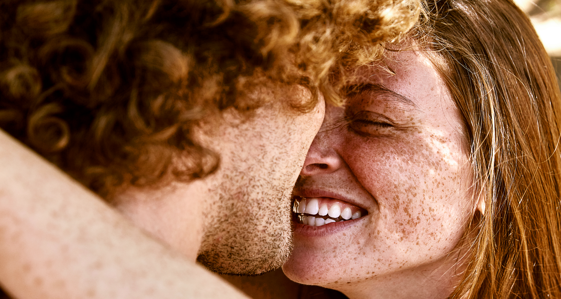 two redheaded people - a man and a woman - hugging and looking at one another